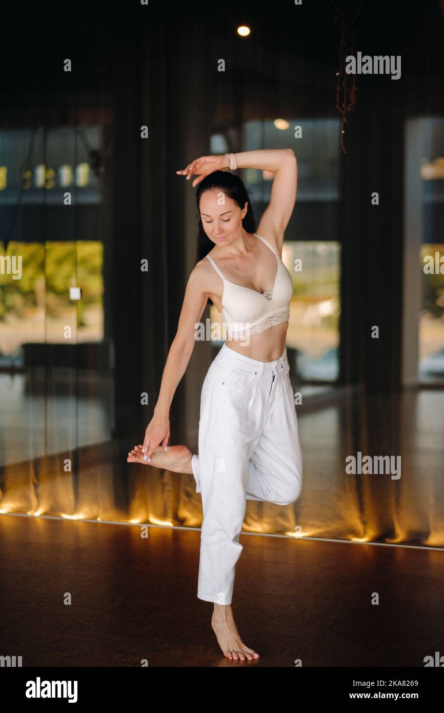 Ritratto di una donna in abiti bianchi che danzano in piedi all'interno Foto Stock