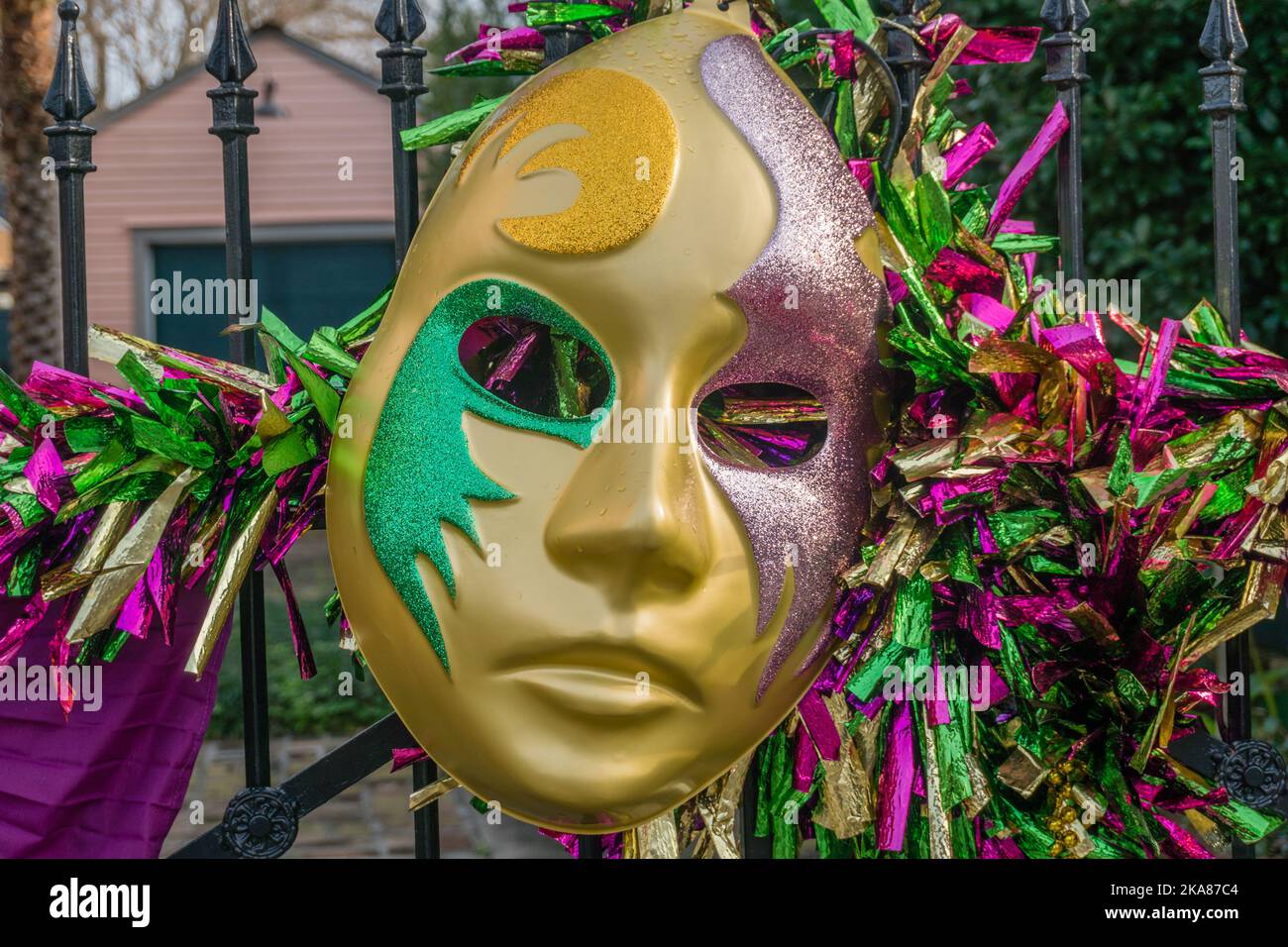 Primo piano di una grande maschera di mardi gras sulla recinzione, una decorazione festiva che segna il festival del Mardi Gras/Carnival ogni primavera a New Orleans, lo Foto Stock