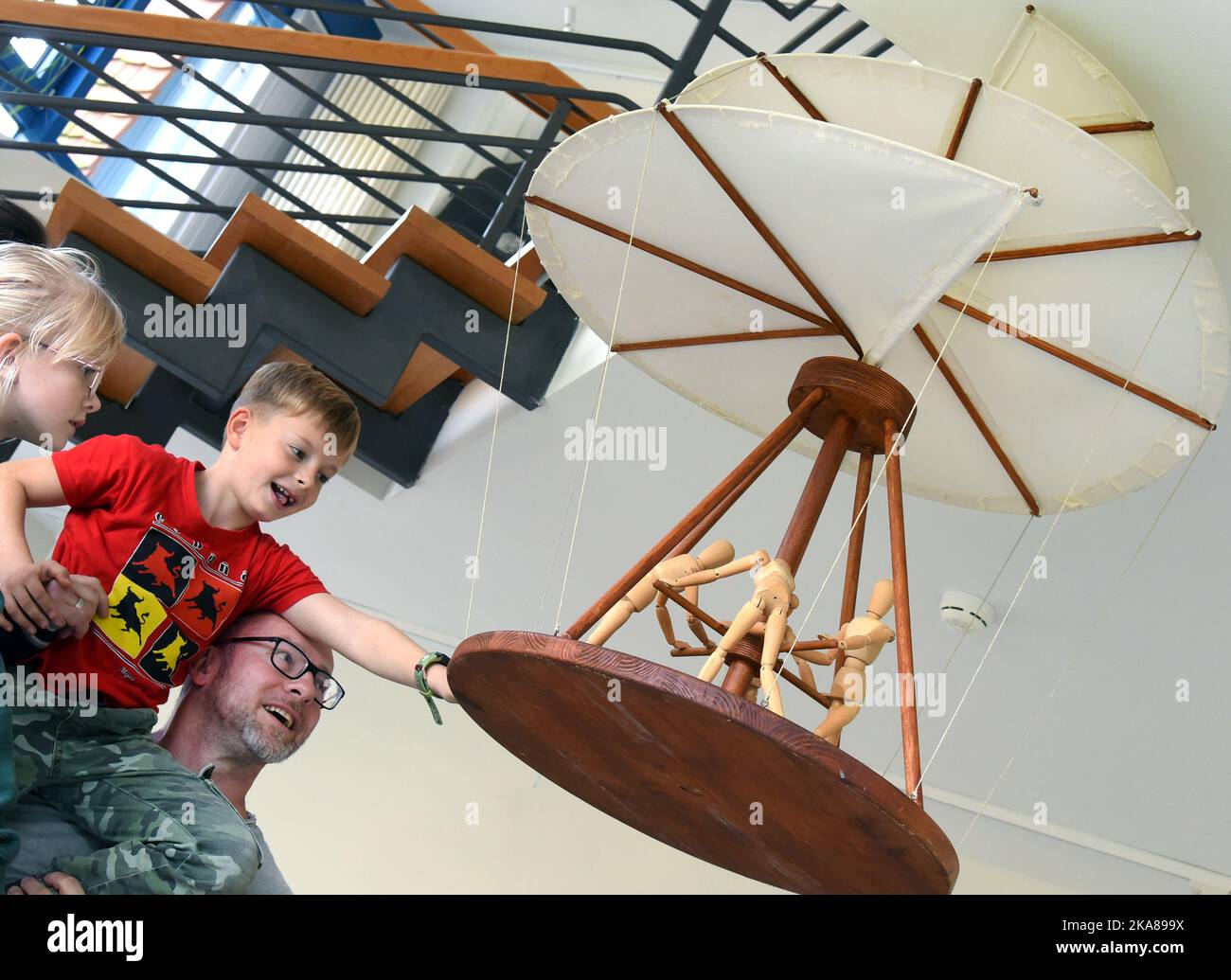 31 ottobre 2022, Sassonia, Grimma: Nella mostra 'da Vinci 500-Moving invenzioni' a Wilhelm Ostwald Park, un padre e i suoi figli guardano un modello di un airscrew realizzato dalla polymath da Vinci (1452-1519), con il quale quattro persone dovrebbero guidare un meccanismo di rotazione e impostare la filatura della vite coperta di tessuto. La mostra aeronautica è uno dei 27 modelli 100 funzionali sviluppati, progettati e costruiti dagli studenti del Dipartimento di Ingegneria e Matematica dell'Università di Bielefeld di Scienze applicate, su schizzi della matematica italiana. Fino a marzo 2023, i visitatori possono Foto Stock