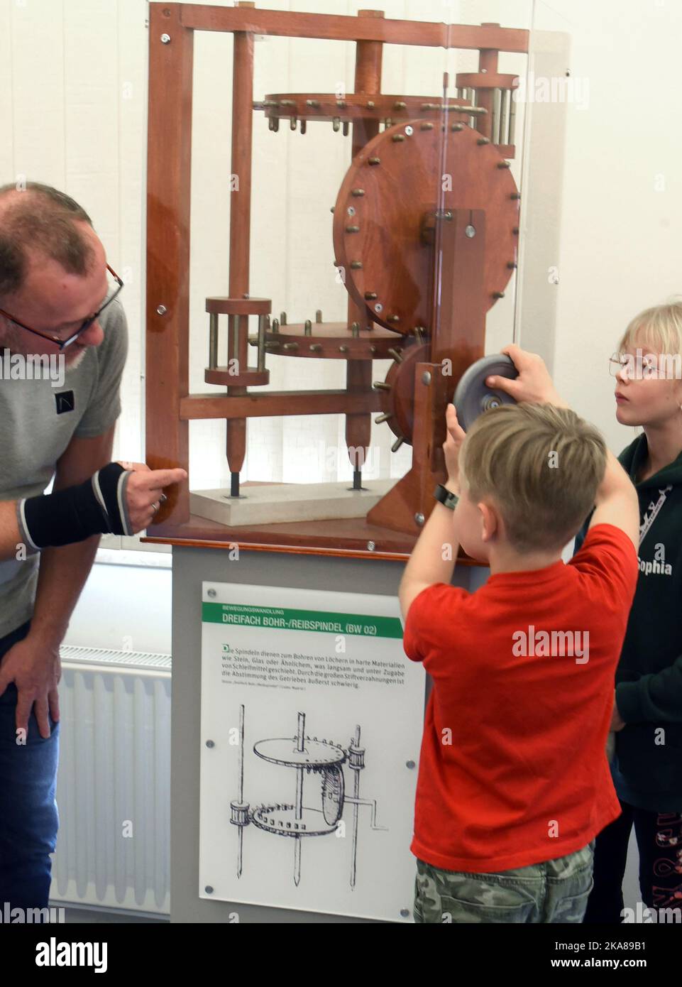 31 ottobre 2022, Sassonia, Grimma: Nella mostra "da Vinci 500 - Moving invenzioni" a Wilhelm Ostwald Park, un padre e i suoi figli provano la funzionalità per la perforazione di fori in materiali duri su un modello di mandrino per alesatura a triplo foro di da Vinci (1452-1519). La mostra è uno dei 27 modelli 100 funzionali sviluppati, progettati e realizzati da studenti del Dipartimento di Ingegneria e Matematica dell'Università di Bielefeld, sulla base di schizzi della matematica italiana. Fino a marzo 2023, i visitatori possono non solo vedere i modelli, ma anche provarli e sottopassarli Foto Stock