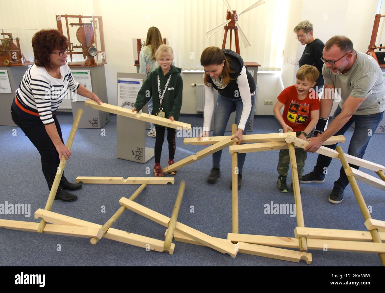 31 ottobre 2022, Sassonia, Grimma: Nella mostra "da Vinci 500-Moving invenzioni" nel Wilhelm Ostwald Park, i visitatori crollano il modello del ponte in legno autoportante di da Vinci (1452-1519), come spiega Ilona Brandt (l), che possono poi ricostruire. La mostra è uno dei 27 modelli 100 funzionali sviluppati, progettati e realizzati da studenti del Dipartimento di Ingegneria e Matematica dell'Università di Scienze applicate di Bielefeld sulla base di schizzi della matematica italiana. Fino a marzo 2023, i visitatori possono non solo visualizzare i modelli, ma anche provarli e un Foto Stock