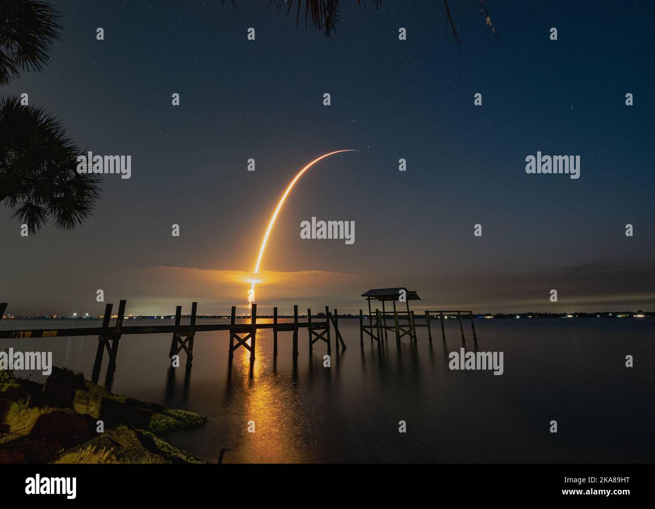 Una bella foto di un molo di legno sulla riva del lago con un lancio missilistico al cielo dell'alba sullo sfondo Foto Stock