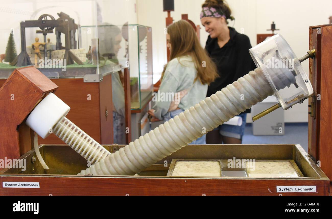 31 ottobre 2022, Sassonia, Grimma: Nella mostra 'da Vinci 500 - Moving invenzioni' nel Wilhelm Ostwald Park, un visitatore si trova con il bambino dietro i sistemi di trasporto dell'acqua - che è attribuito all'inventore greco Archimedes (287 a.C., l) ed è stato ulteriormente ottimizzato dalla polymath italiana da Vinci (1452-1519) (r). La mostra è uno dei 27 modelli 100 funzionali sviluppati, progettati e realizzati da studenti del Dipartimento di Ingegneria e Matematica dell'Università di Bielefeld, sulla base di schizzi della matematica italiana. Fino a marzo 2023, i visitatori possono Foto Stock
