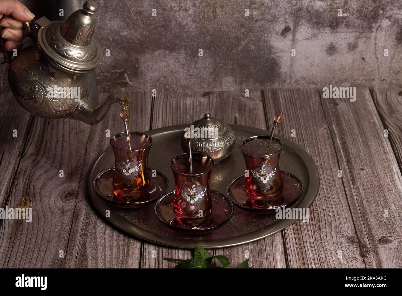 Serve tè moresco caldo su un vassoio con bicchieri e caraffa su un tavolo di legno Foto Stock