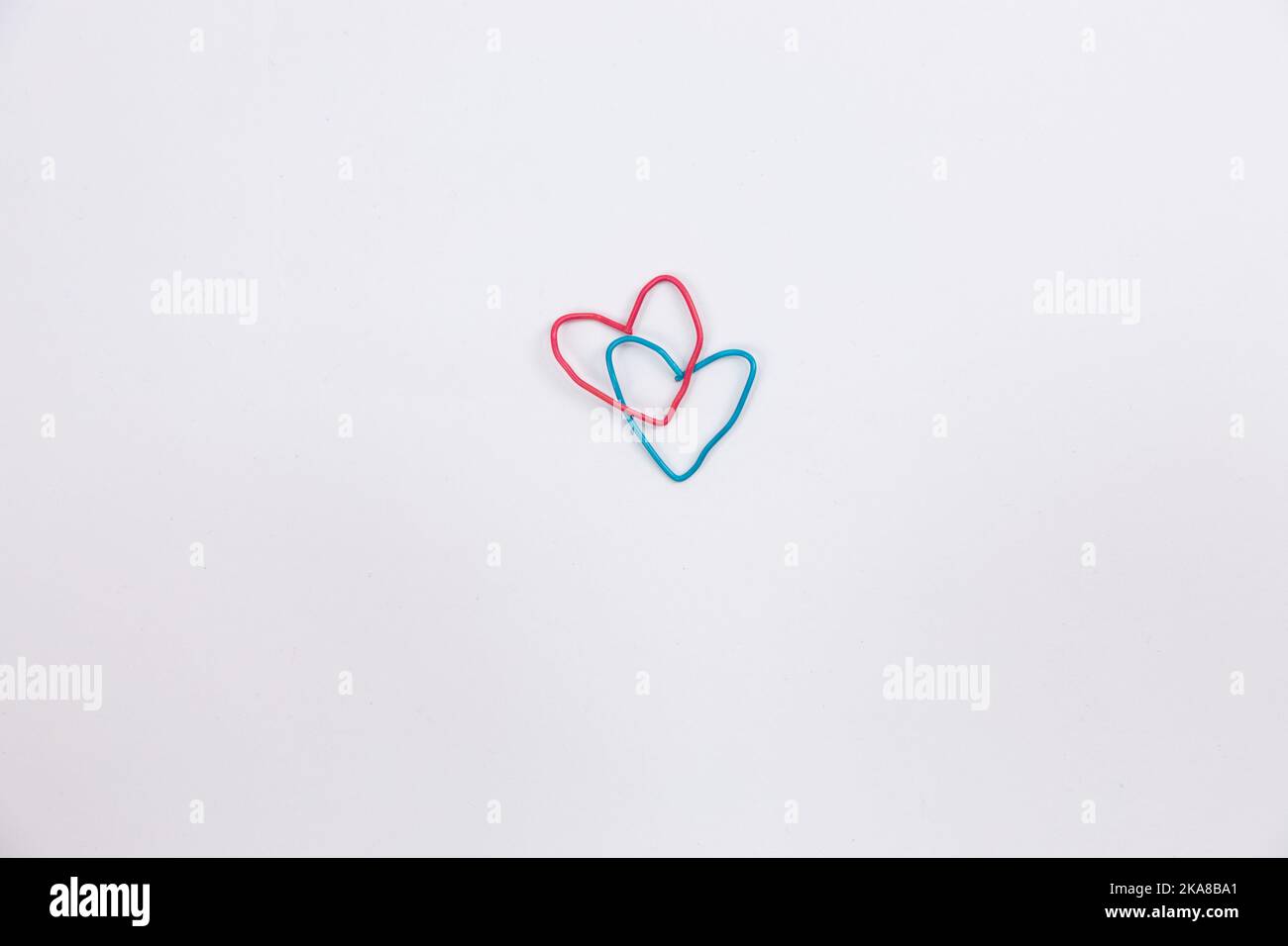 Una graffetta blu e rossa a forma di cuore su sfondo bianco isolato. Foto di alta qualità Foto Stock