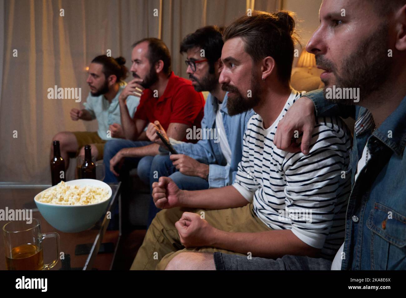 Gruppo di maschi si è concentrato seduto sul divano in un soggiorno guardando una partita di calcio Coppa del mondo. Foto Stock