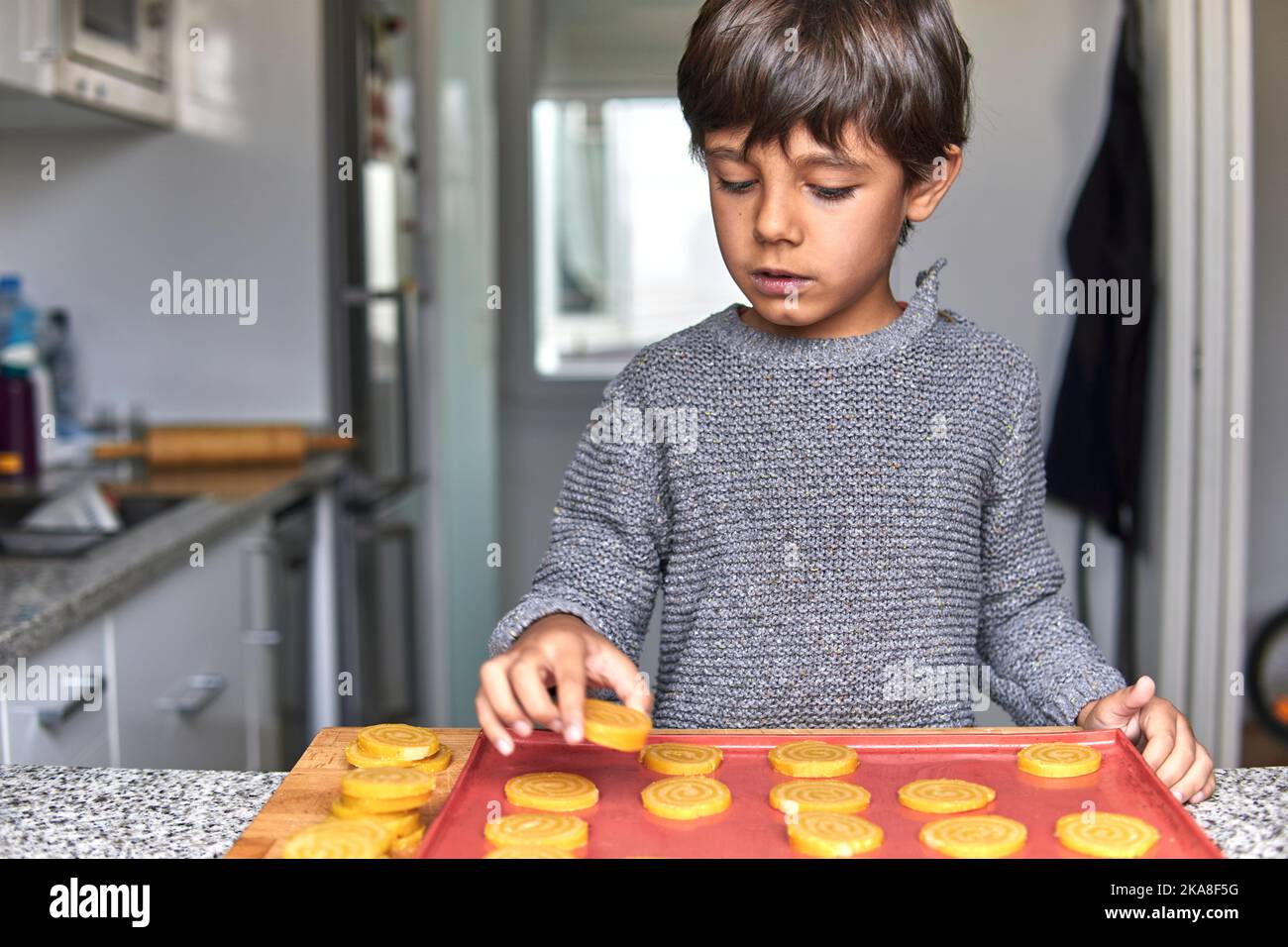 ragazzo di età elementare che fa biscotti in inverno Foto Stock