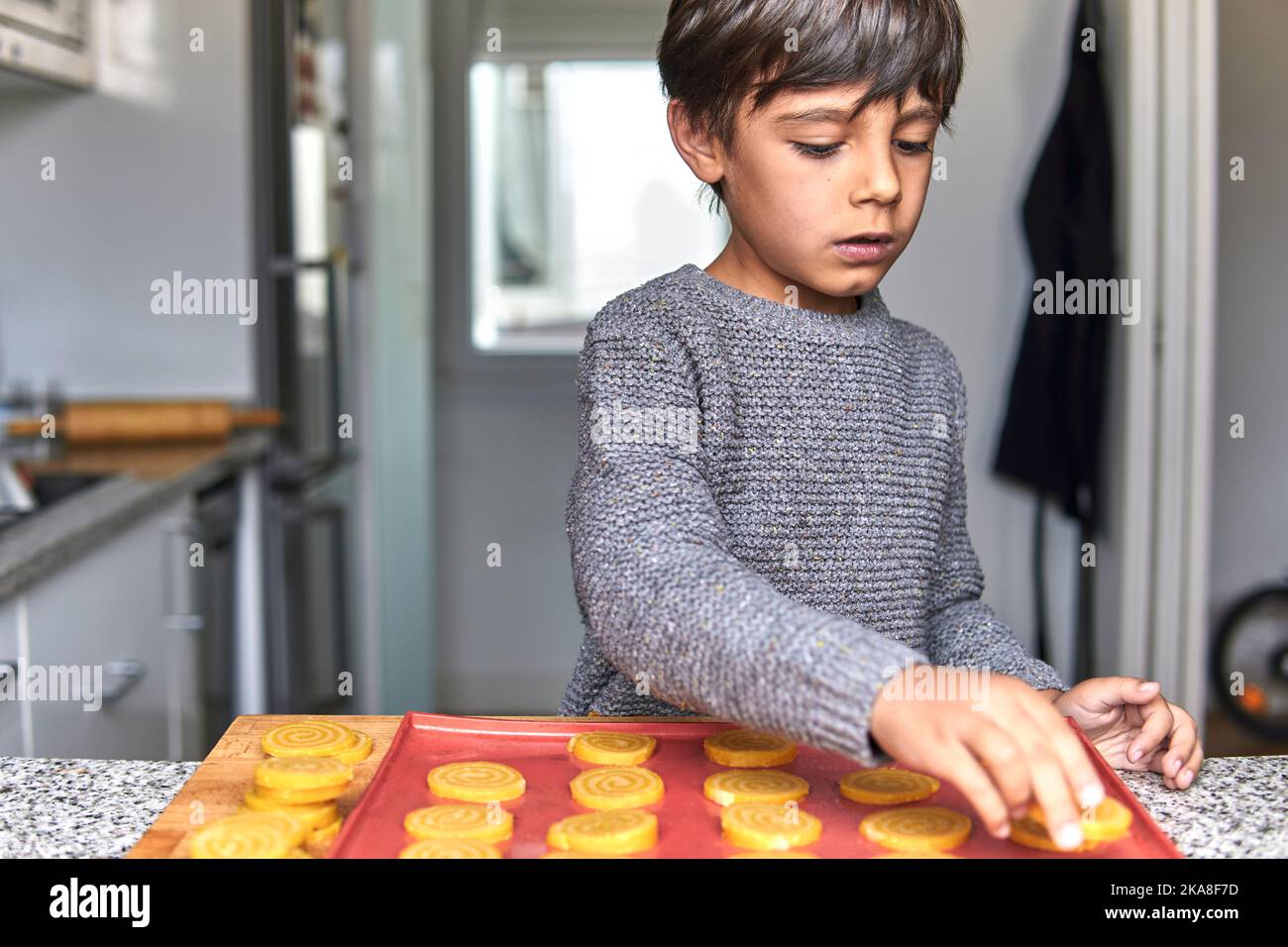 ragazzo di età elementare che fa biscotti in inverno Foto Stock