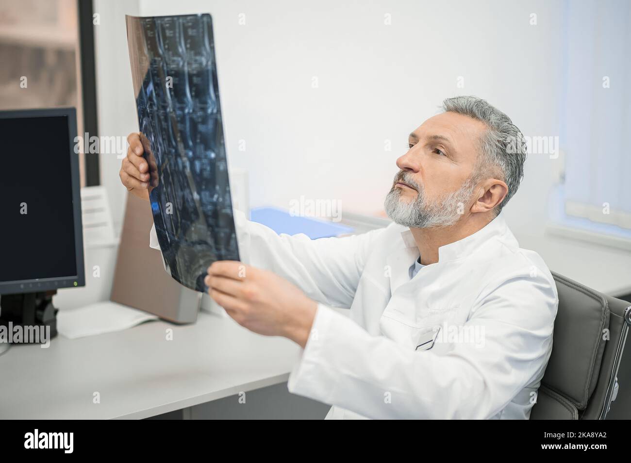 Medico di sesso maschile che esamina i risultati di MRI Foto Stock