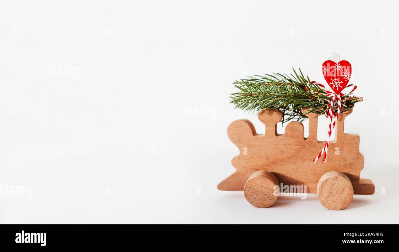 Treno in legno con rami di abete legati e decorazione a cuore rosso. Grazioso simbolo dell'albero di Natale portato a casa per la celebrazione di Capodanno. Vacanze invernali Foto Stock