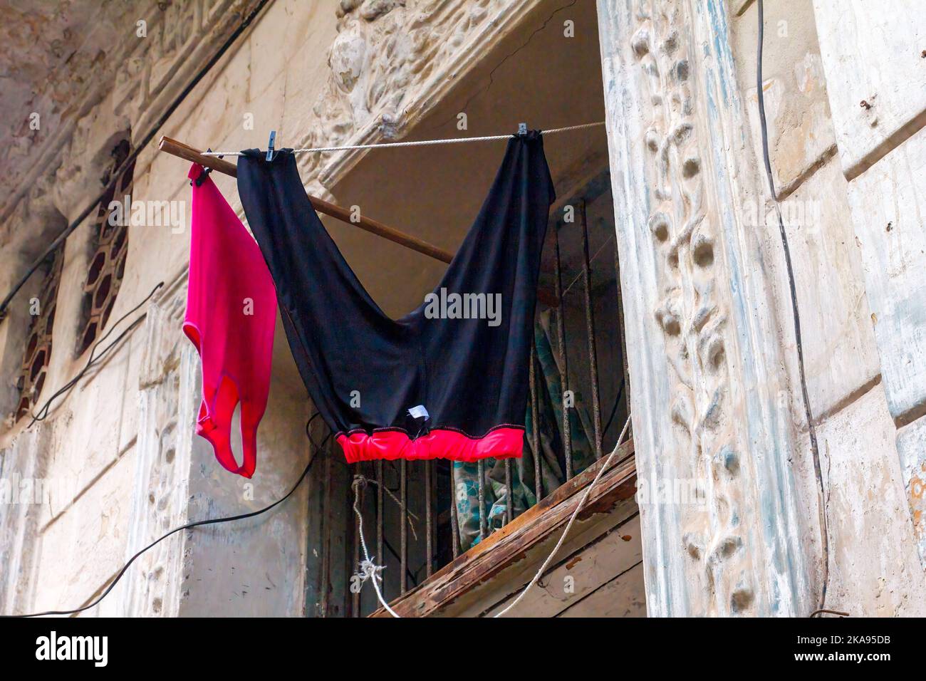 Due capi di abbigliamento appendono fuori da una finestra di un edificio. La parete esterna è intaccata e non dipinta. Foto Stock