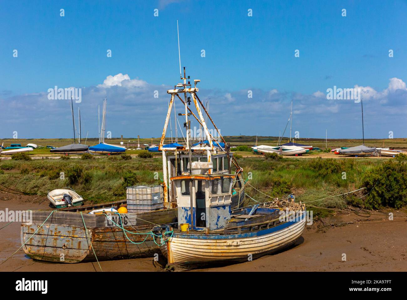 Barche ormeggiate di fronte alle paludi di sale pianeggianti a Brancaster, sulla costa nord del Norfolk, nell'Inghilterra orientale del Regno Unito. Foto Stock