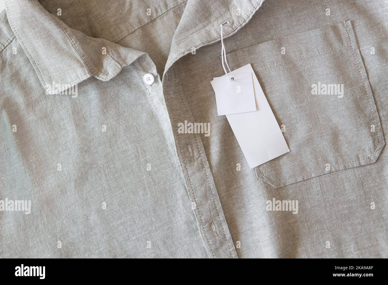 Etichetta di prezzo vuota scheda di carta su camicia di lino naturale. Modello tag tag tag abbigliamento con spazio copia per marca, testo, prezzo. Vista dall'alto, copia Foto Stock