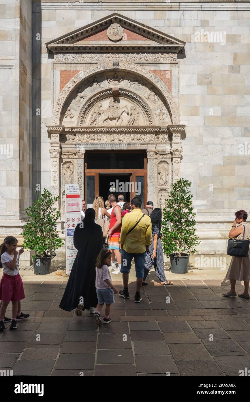 Duomo di Como persone, vista delle persone che si trovano in coda in Via Maestri Comacini per entrare nella Cattedrale di Como dalla sua porta sud, Lombardia, Italia Foto Stock