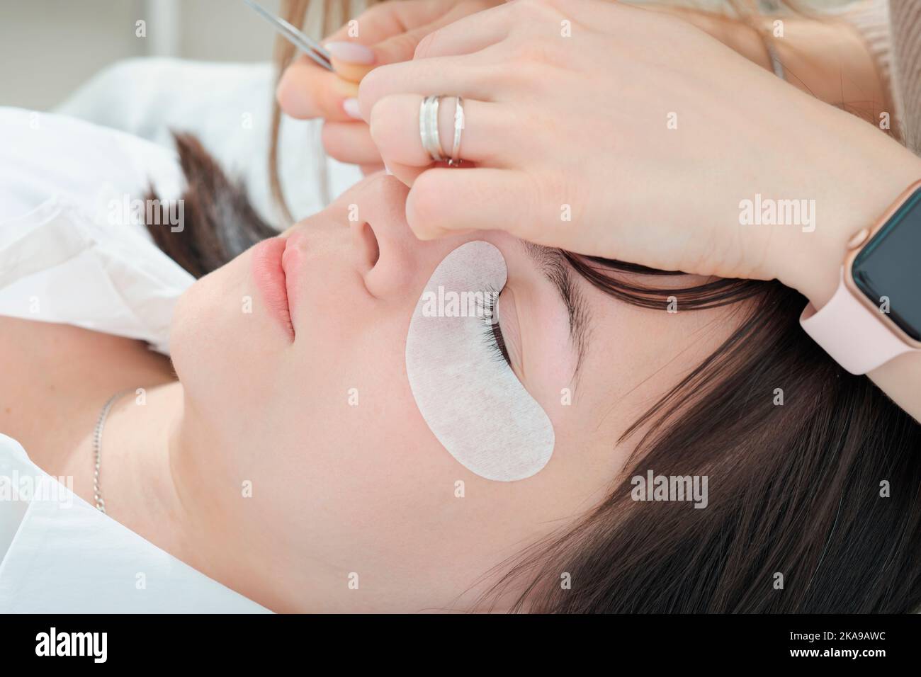 primo piano della donna caucasica che si trova con l'occhio chiuso durante la procedura di estensione del lash. dettagli del processo di creazione del lash falso Foto Stock