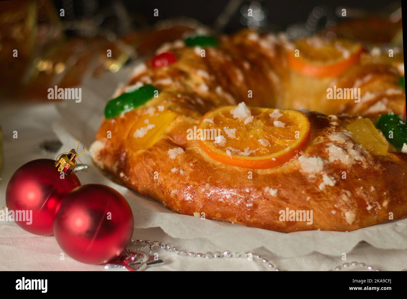 Un roscón reyes fatto in casa con frutta candita e zucchero perla su un tavolo decorato con motivi natalizi Foto Stock