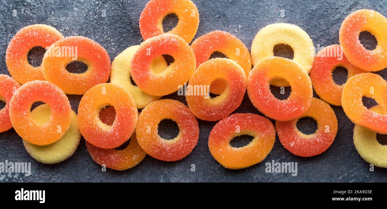Una vista stretta di anelli di gommoso al gusto di pesca ricoperti di zucchero e dai colori vivaci. Foto Stock