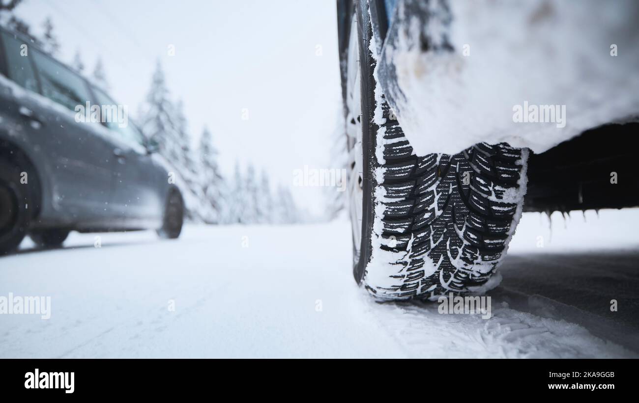 Vista ravvicinata dello pneumatico della vettura su strade innevate e ghiacciate. Temi sicurezza e guida in inverno. Foto Stock
