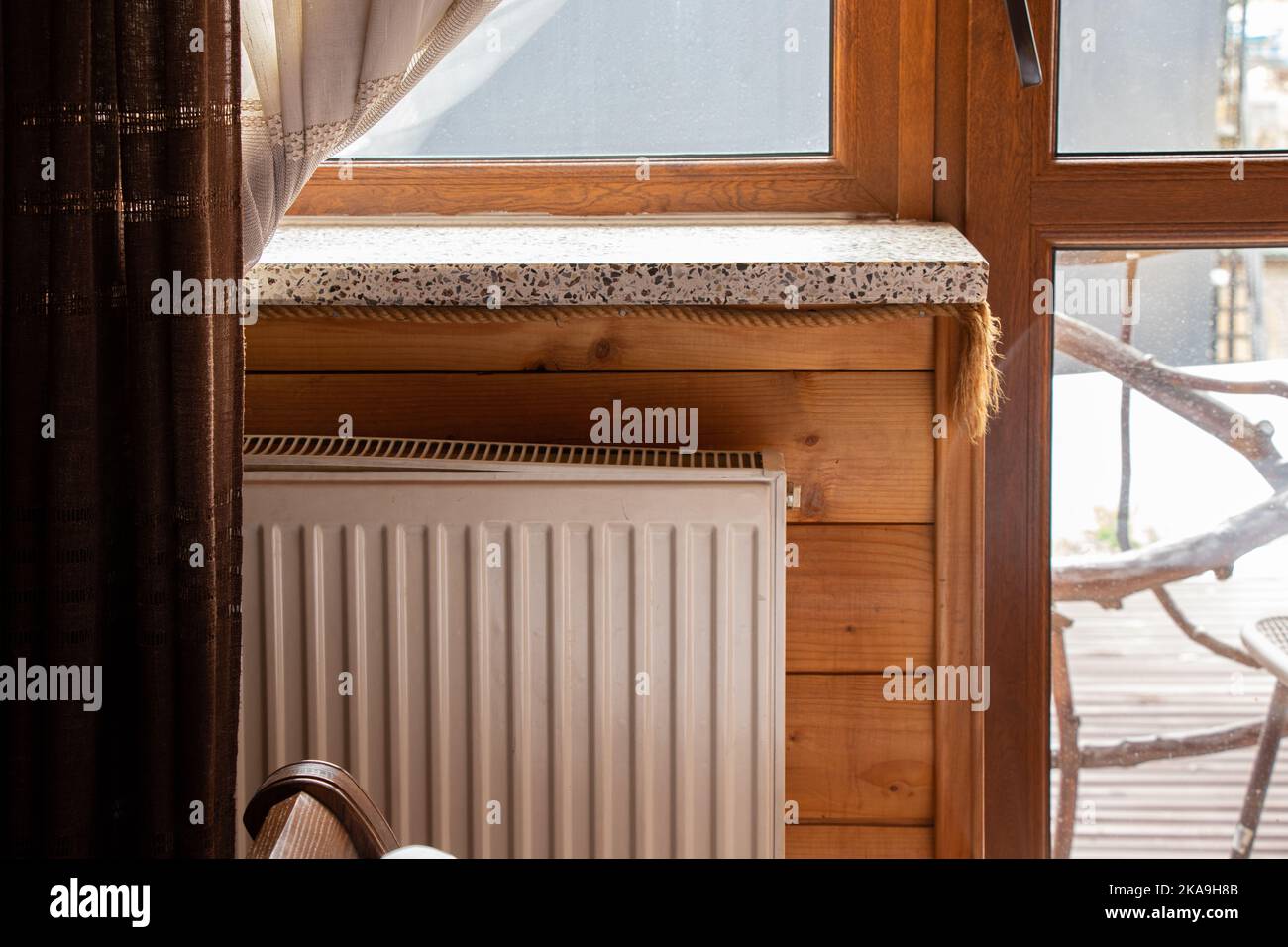 Batteria calda vicino alla finestra in un appartamento con pareti di legno, riscaldamento stagione in Ucraina, casa Foto Stock