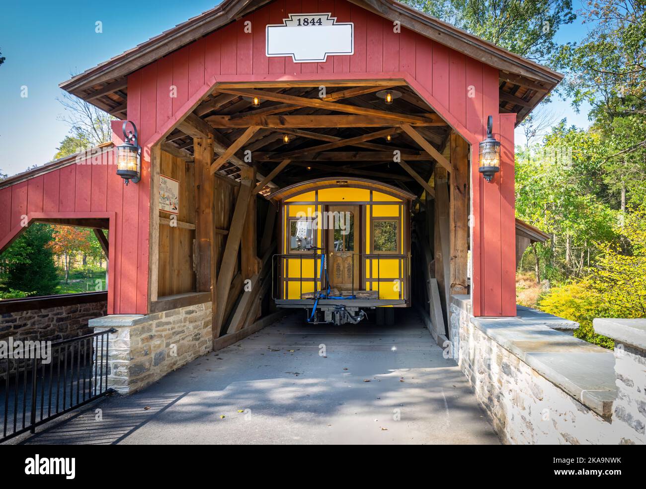 Installazione di un nuovo passeggero giallo pullman d'antiquariato attraverso un ponte di copertura su un binario ferroviario in un giorno di autunno Foto Stock