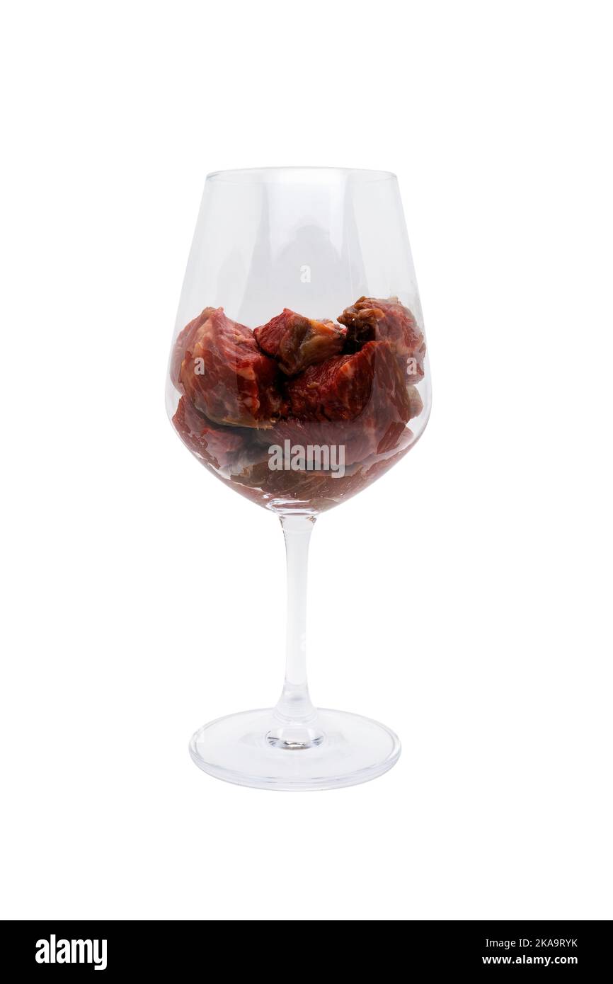 Bicchiere di vino rosso riempito con pezzi di carne rossa. Isolato su sfondo bianco con tracciato di ritaglio. Foto Stock
