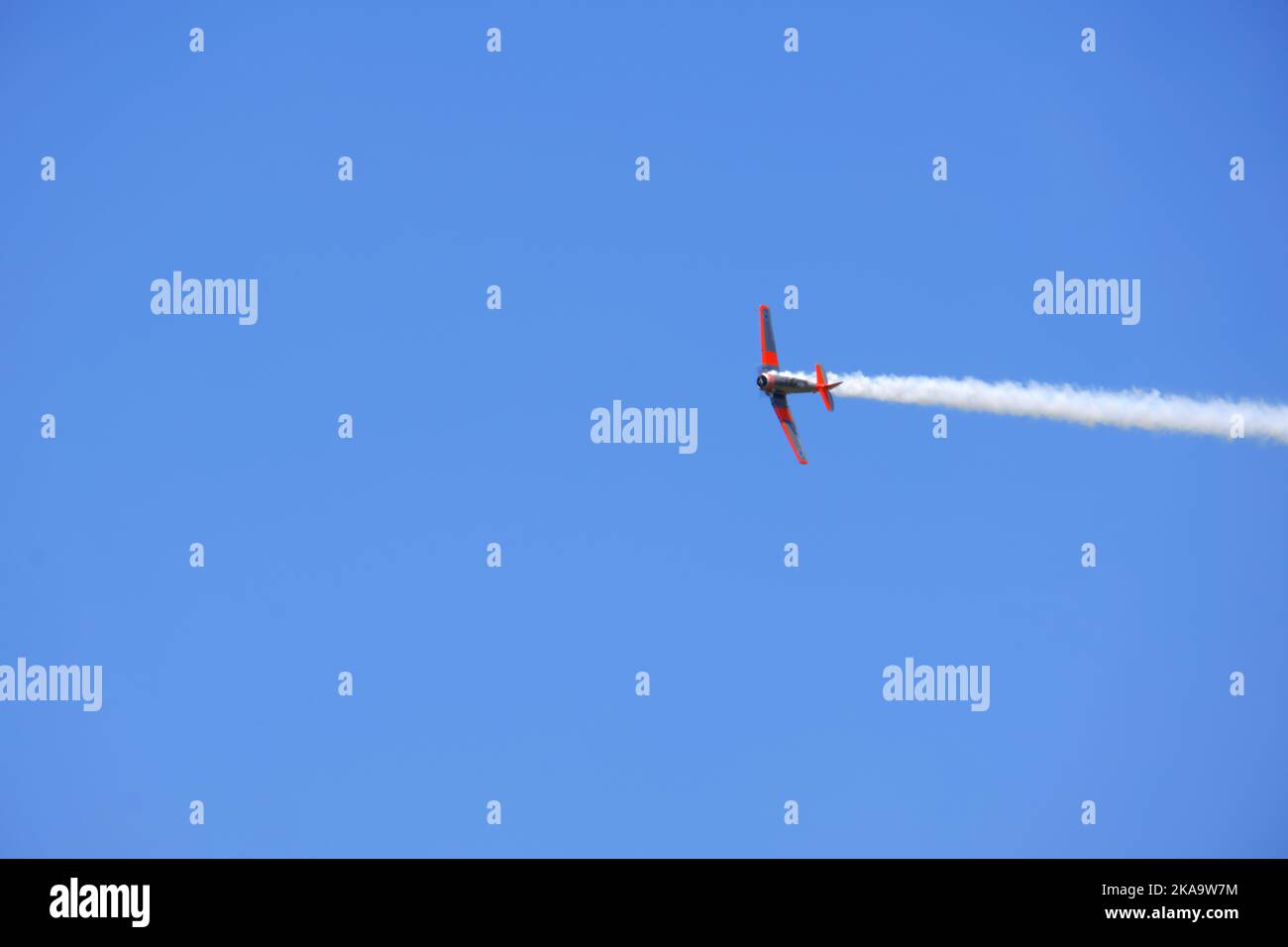 Aereo che vola con fumo sulla coda al cielo blu con le nuvole Foto Stock