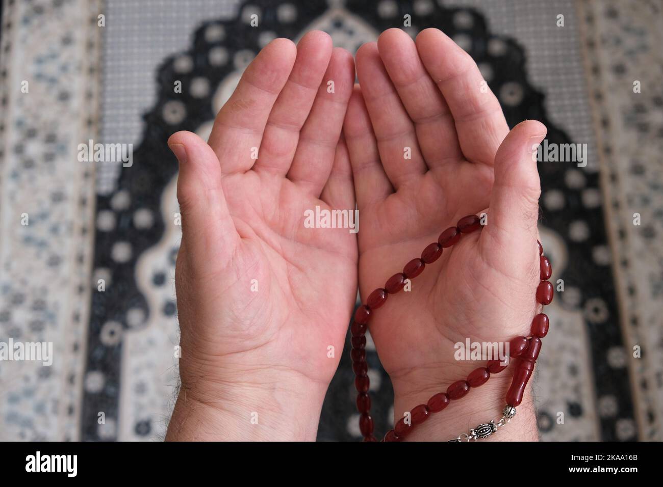 Un uomo anziano che prega sul tappeto di preghiera semplicemente mostrando le mani con perline di preghiera. Mani ravvicinate con perle che pregano per Dio. İslamic concetto backgroun Foto Stock