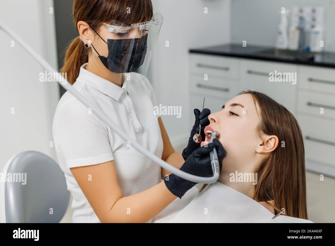 Dentista con paziente durante l'esame dei denti. Clinica odontoiatrica moderna. Concetto di igiene orale professionale, consultazione in studio stomatologico Foto Stock