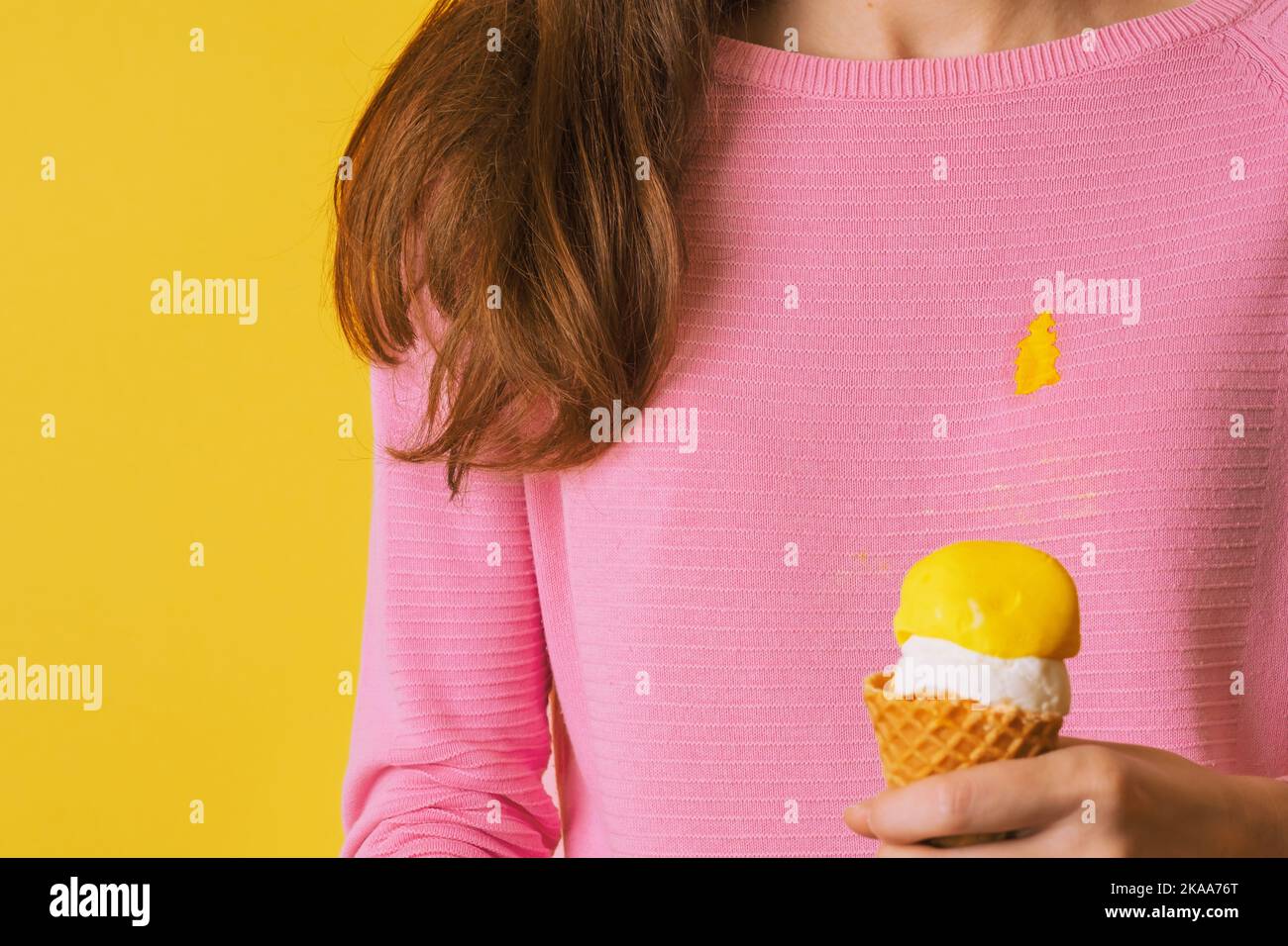 La ragazza che indossa blusa macchiata che tiene gelato. Versare il gelato sui vestiti Foto Stock