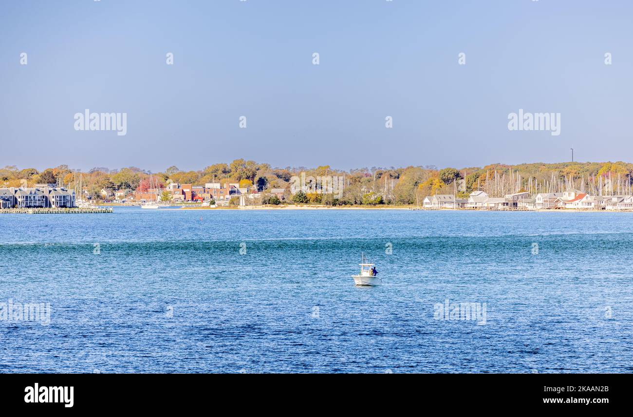 Piccola barca con gente che pesca e Greenport in lontananza Foto Stock
