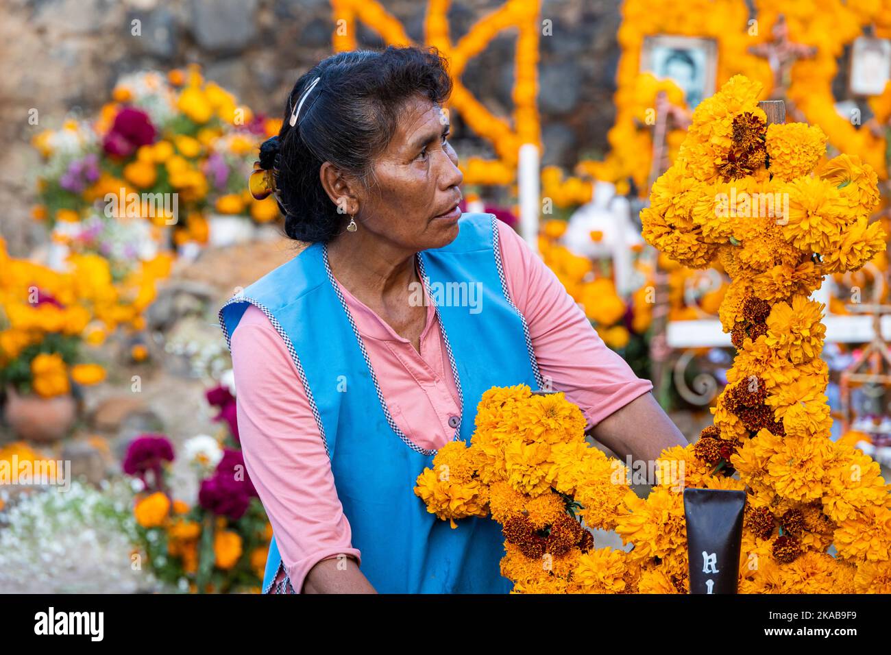 Morelia, Messico, 1 novembre 2022, Una donna Pureecha con fiori di marigold durante la celebrazione del giorno dei morti nel cimitero di Arocutin, Michoacan, Messico. Gli indigeni Pureecha di questo villaggio preparano questo rituale annuale del ricordo costruendo altari con marigolds, candele e il cibo o la bevanda favoriti del defunto. La veglia si svolge la notte del 1st novembre ed è diventata una grande attrazione turistica nello stato messicano centrale di Michoacan. Brian Overcast/Alamy Live News Foto Stock