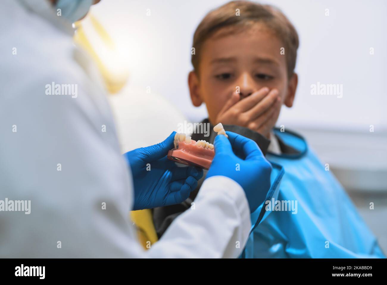 Non riesco a crederci. Un ragazzino sorpreso che tiene chiusa la bocca mentre guarda un dente che il dentista ha appena tirato fuori. Foto Stock