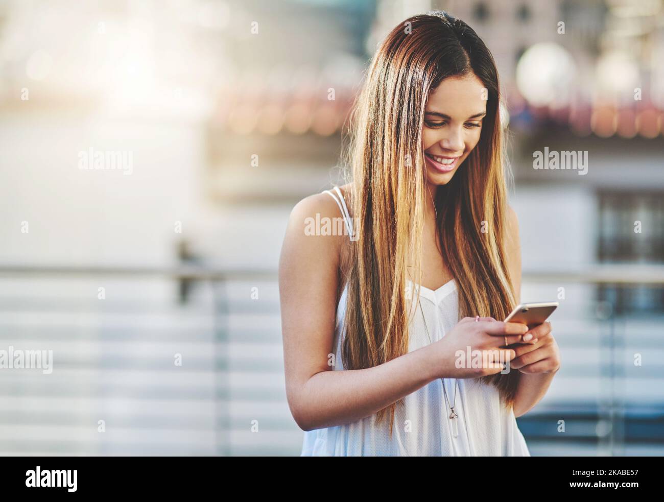 Risponde ad ogni messaggio: Una giovane donna attraente che invia un messaggio di testo mentre si è in piedi fuori. Foto Stock