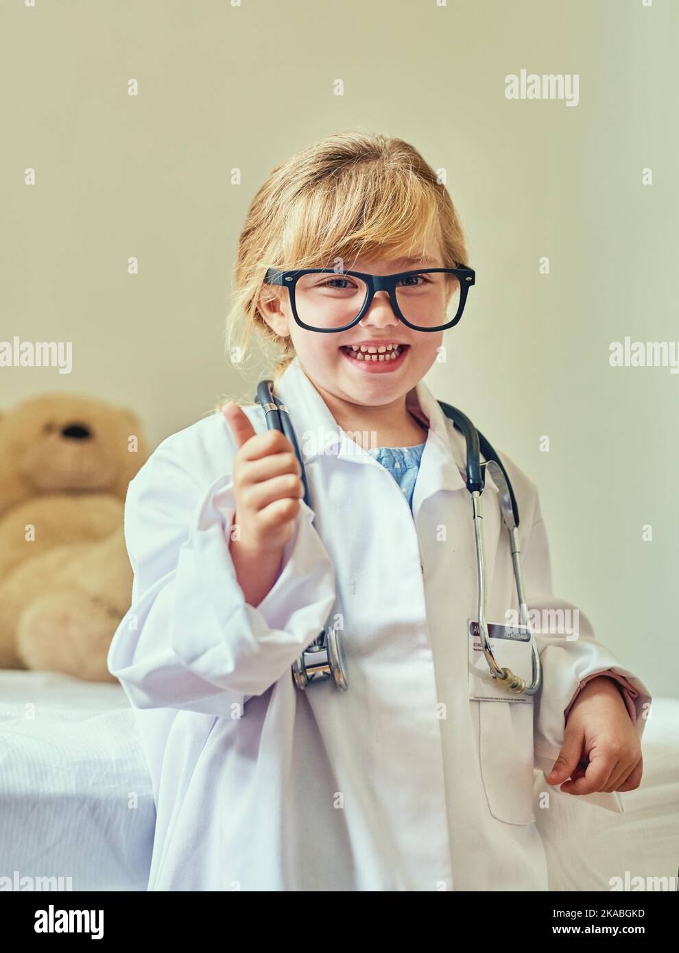 Assistenza sanitaria di qualità per i bambini approvata dai bambini. Ritratto di un'adorabile bambina vestita da medico e che mostra un gesto di pollice in su. Foto Stock