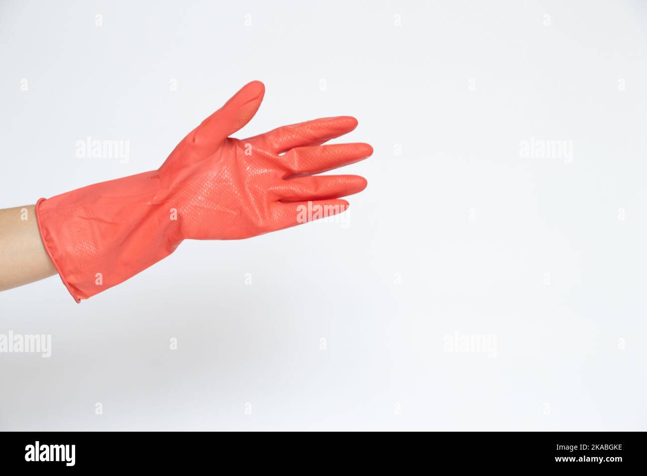 Mano femmina in un guanto da cucina rosa su sfondo bianco, lavori di casa, pulizia della casa Foto Stock