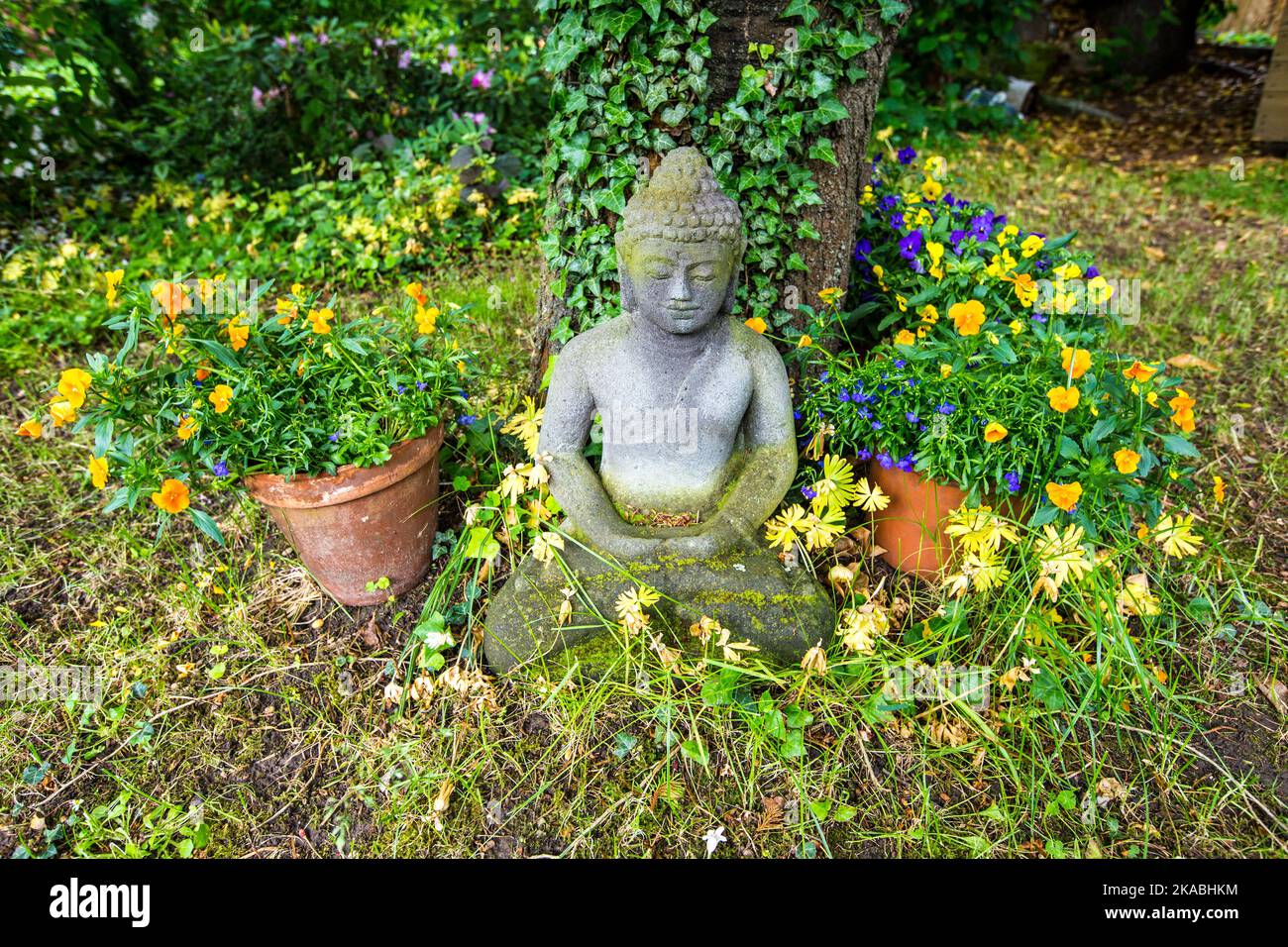 statua di buddha in posizione seduta sotto un albero di ciliegio Foto Stock