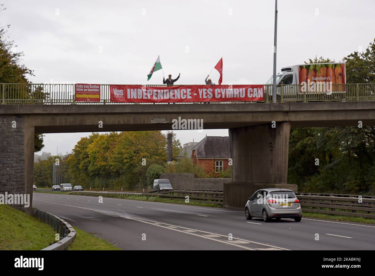 I sostenitori di un'indipendenza gallese si votano con bandiere e bandiere gallesi sul ponte stradale A40 a Carmarthen, Galles Foto Stock