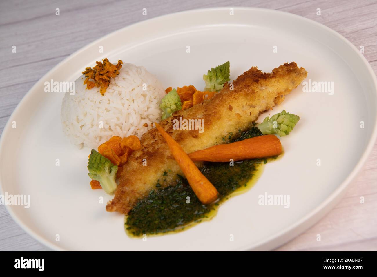 Ricetta per filetto di nasello impanato con panko, riso, patatine di carote e salsa di coriandolo Foto Stock