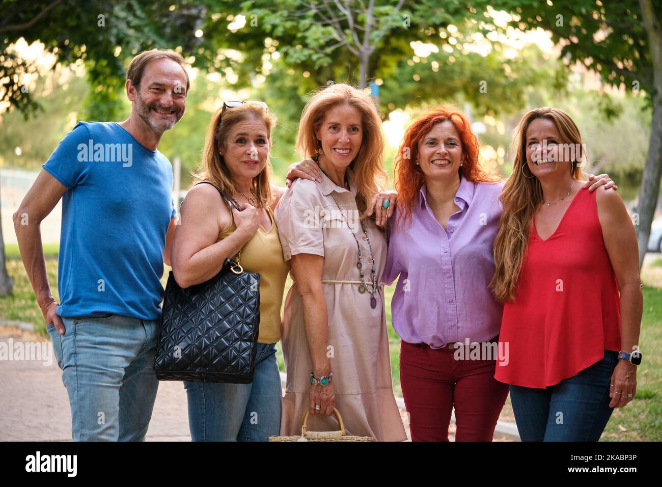 Cinque adulti adulti adulti che guardano la macchina fotografica in un parco. Foto Stock