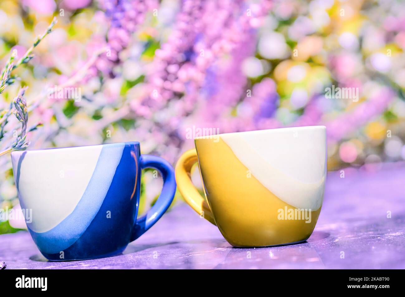 Tazze da tè da caffè gialle e blu su sfondo floreale rosa Foto Stock