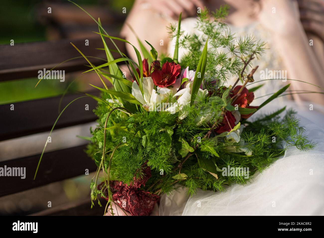La sposa tiene un bouquet di nozze dalle rose nelle sue mani, fiori di giorno di nozze. Bel bouquet di fiori bohémien matrimonio. Ragazza in un abito con un bouq Foto Stock
