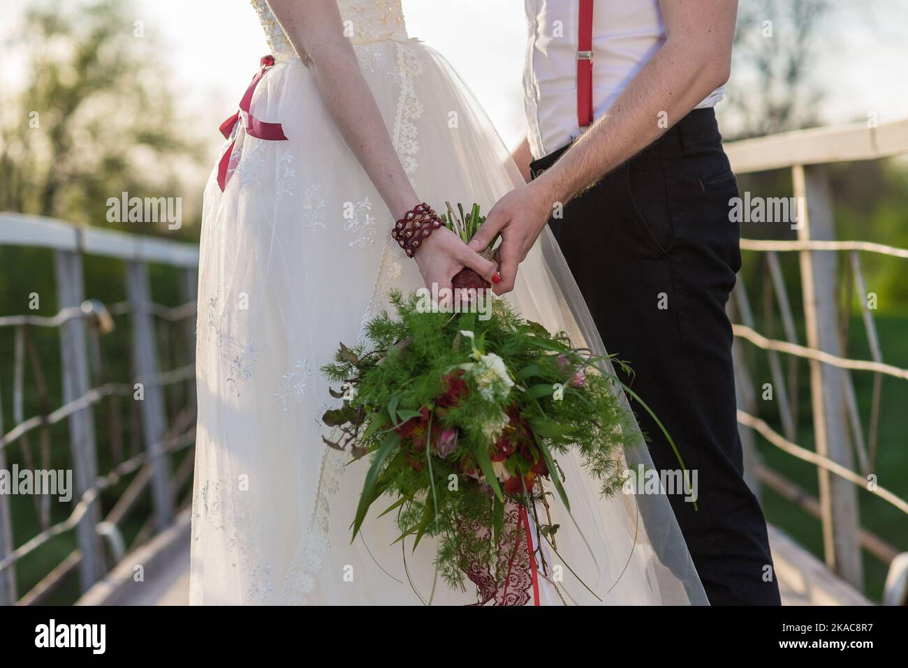 La sposa tiene un bouquet di nozze dalle rose nelle sue mani, fiori di giorno di nozze. Bel bouquet di fiori bohémien matrimonio. Ragazza in un abito con un bouq Foto Stock