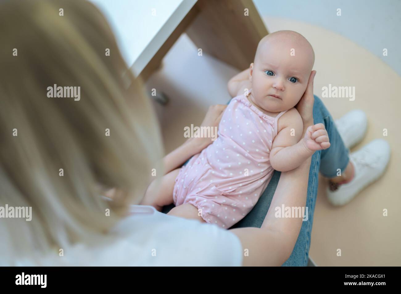 mamma bionda che parla con un pediatra maschio e tiene il suo bambino Foto Stock