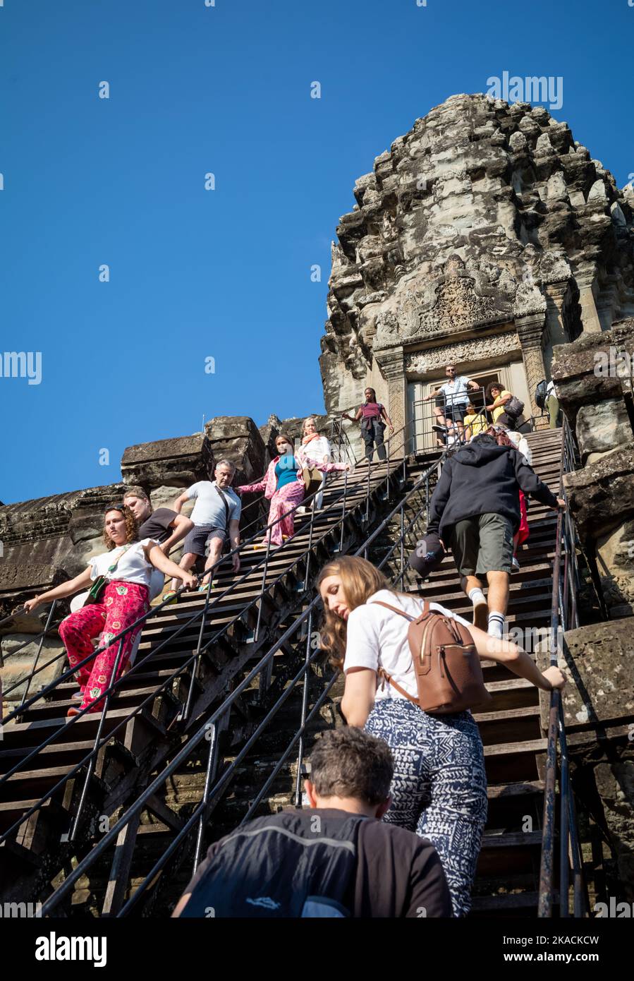 Angkor Wat, Cambogia, 2 Nov 2022. Turisti stranieri su una scala estremamente ripida come si visita la torre interna al famoso Angkor Wat in Cambogia, 2 novembre 2022. Il turismo sta gradualmente facendo un ritorno, con circa 1.000 visitatori stranieri che arrivano ogni giorno, ma questo è ancora solo una frazione dei circa 6,5 milioni che hanno visitato nel 2019 prima della pandemia del Covid-19. Per i turisti che vengono possono vivere un'esperienza unica e senza affollamento, ma l'economia locale, così dipendente dal turismo, continua a soffrire. Foto Stock