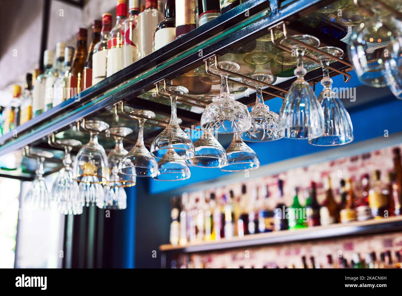 Dove vanno i bicchieri. Un bar immacolato con molte bottiglie e bicchieri senza persone. Foto Stock