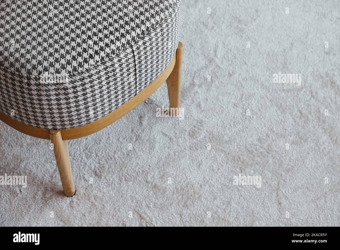 Pouf a scacchi con gambe in legno su soffice tappeto, vista dall'alto con spazio libero, arredamento moderno in soggiorno, design Foto Stock