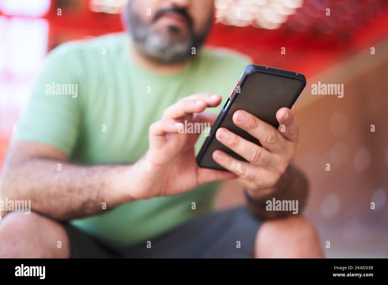 Primo piano di un uomo irriconoscibile che utilizza il telefono all'aperto. Focus sulla cella. Utilizzare il cellulare per controllare le sue scommesse. Foto Stock