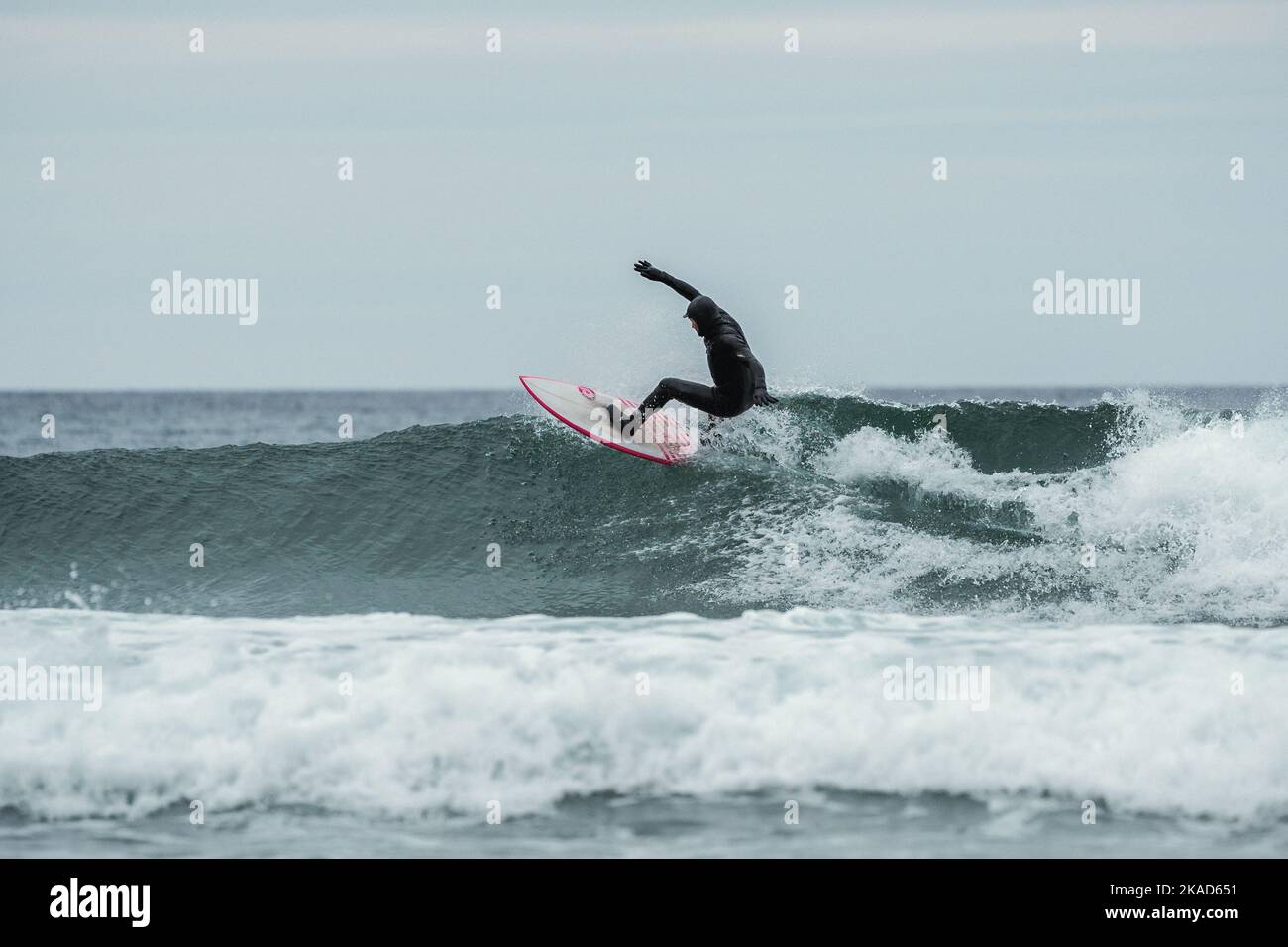 Surfista cavalcando onde di medie dimensioni in condizioni artiche a Unstad Lofoten Norvegia Foto Stock