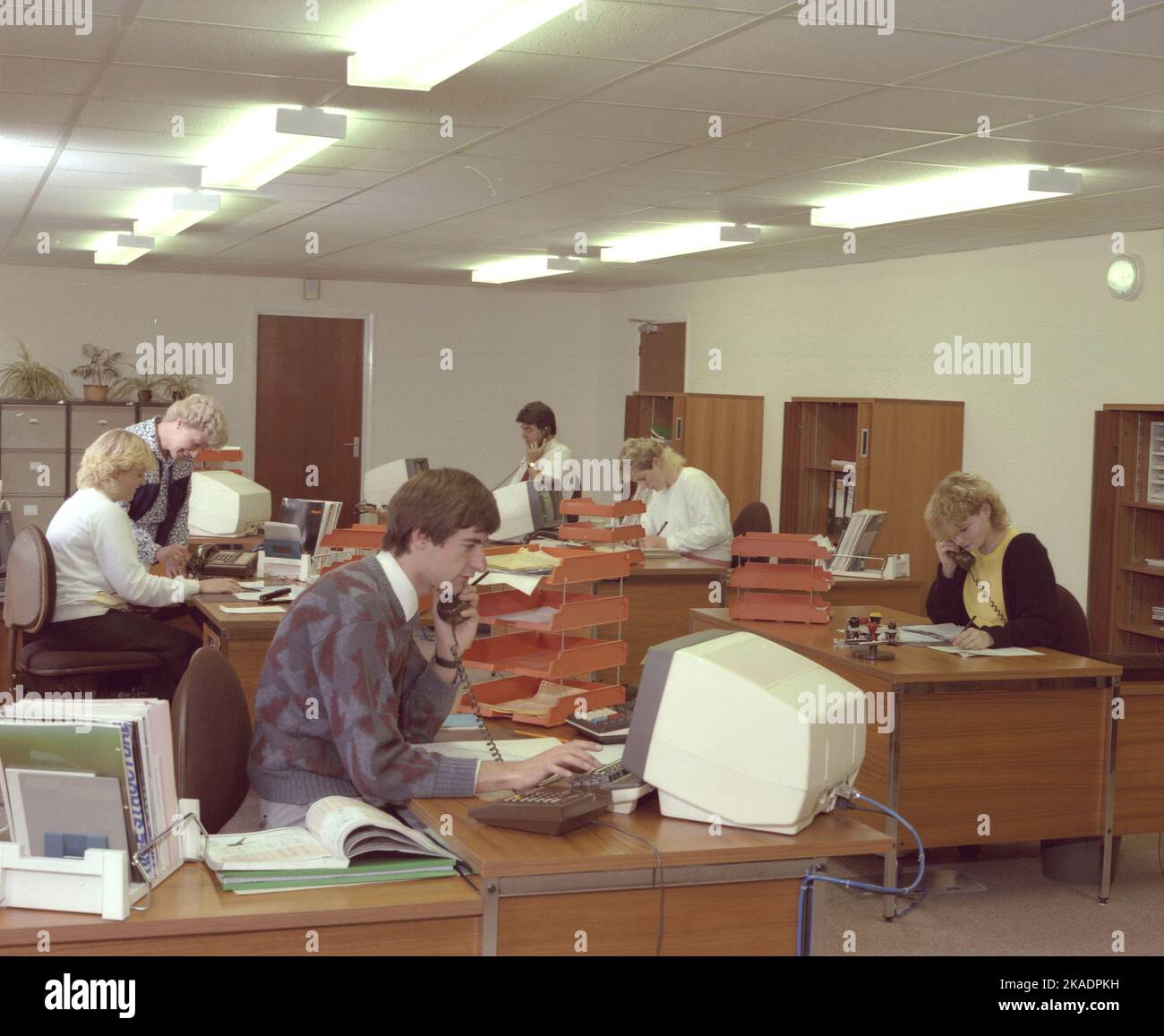Circa 1989, storico, open-plan Office, dipendenti maschi e femmine che lavorano alle scrivanie, alcuni al telefono e utilizzando computer terminali dell'epoca, Inghilterra, Regno Unito. Foto Stock