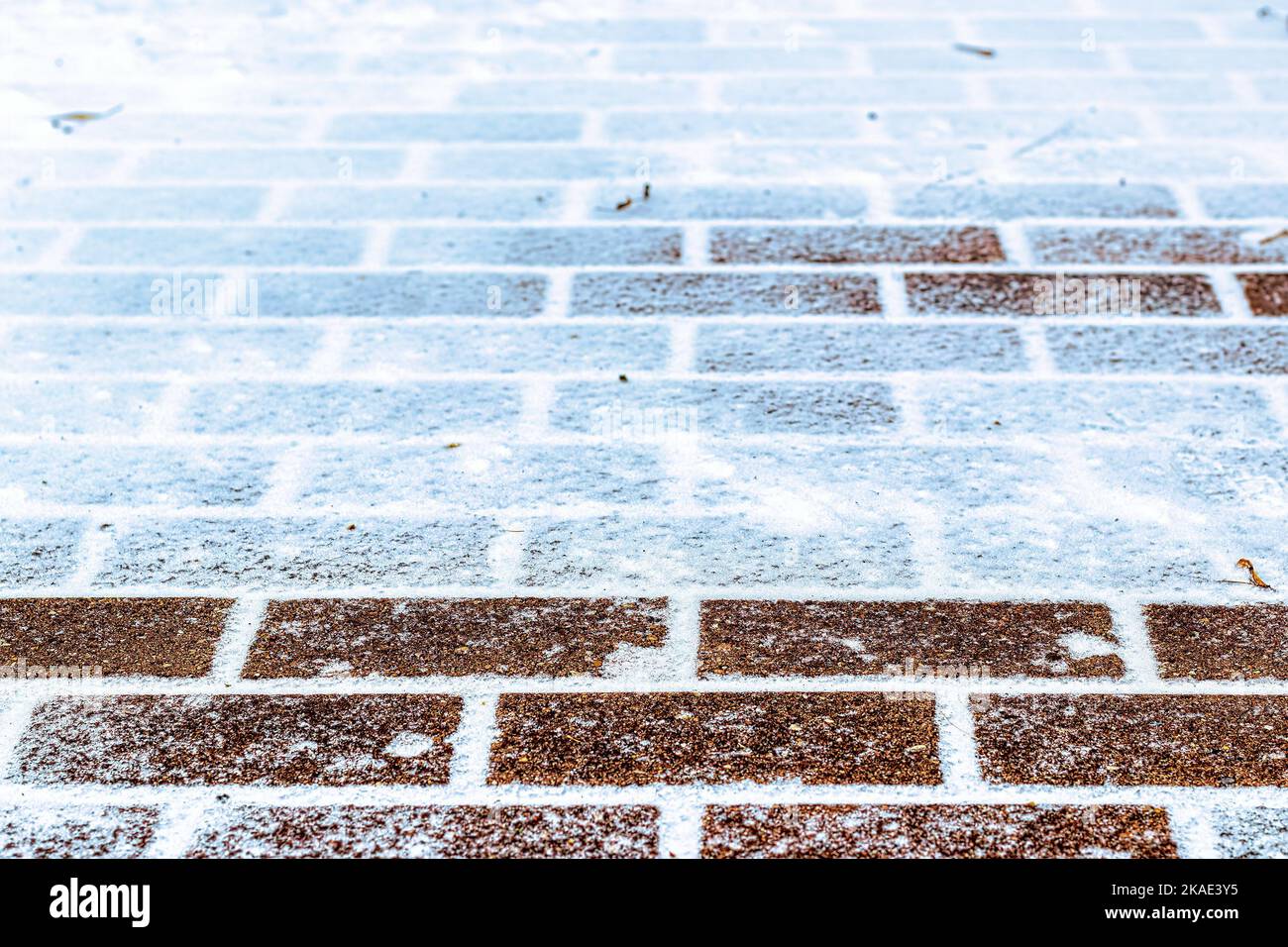 La tessitura del sentiero lastricato coperto dalla prima neve in inverno. Sfondo astratto invernale. Foto Stock